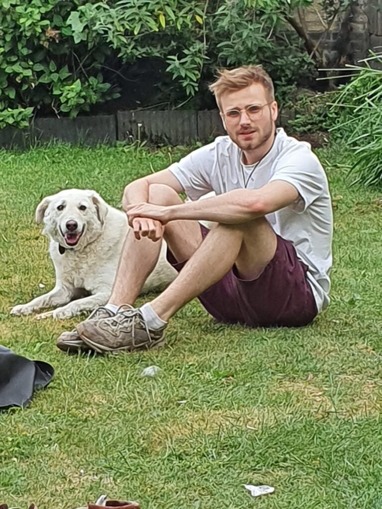 Daan Boleij in het gras met een witte hond